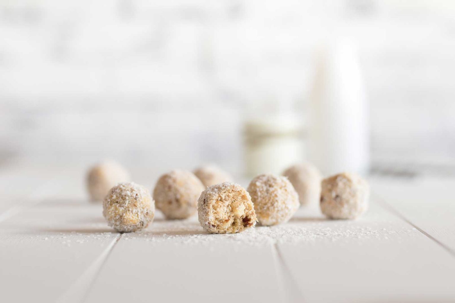 Coconut covered bliss balls on white board