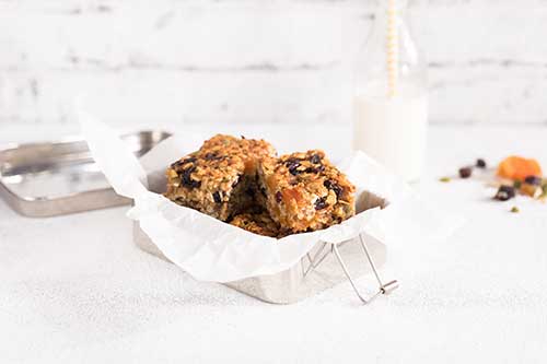 Image of bake flapjacks on baking paper in a baking tray with a bottle of milk and straw on the side