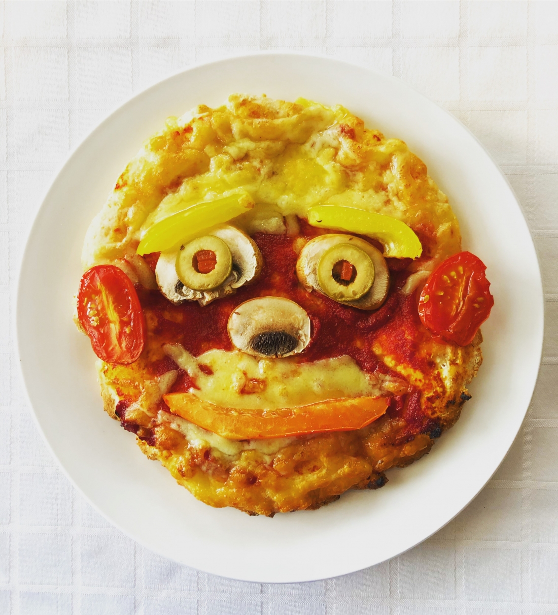 Pizza with colourful vegetables in the shape of a face