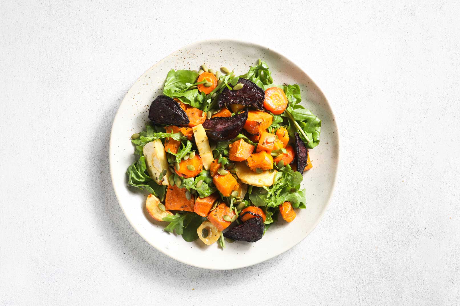 Image of a roasted vegetable salad on a white plate shot from