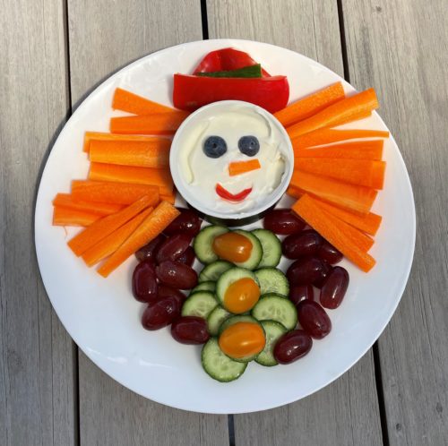vegie crudites and a bowl of tzatziki arranged to look like a snowperson