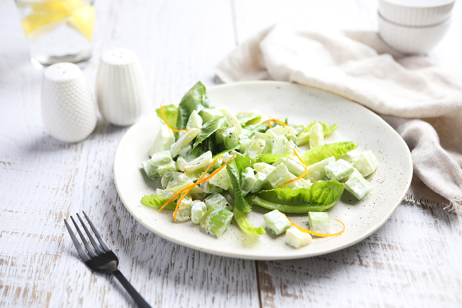 Image of waldorf salad on a white plate with a fork, white cloth napkin and salt and pepper shakers