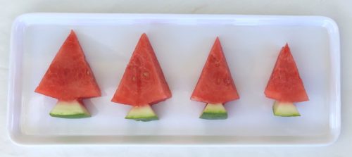 Four watermelon slices cut into Christmas tree shapes