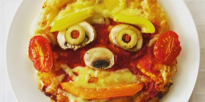 Pizza with colourful vegetables in the shape of a face