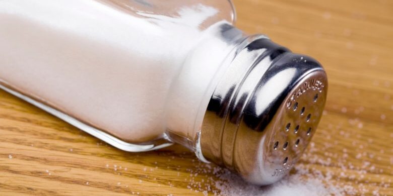 Salt shaker spilling salt onto a table