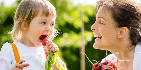 toddler with mum, eating fresh vegetables