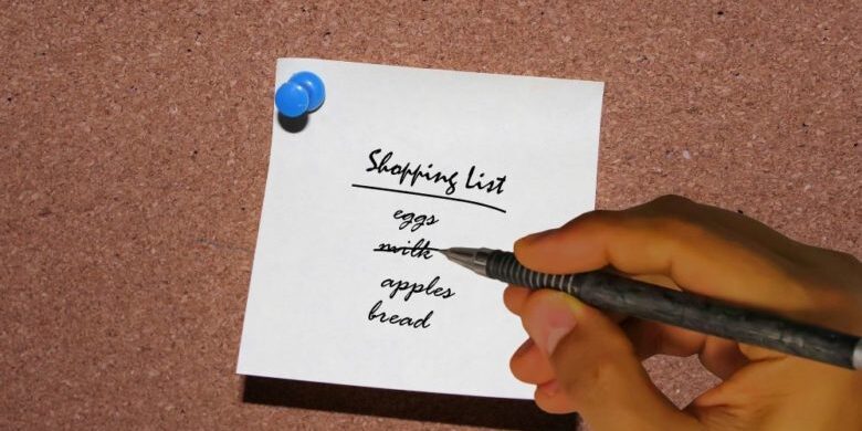 Hand writing a shopping list with a black pen
