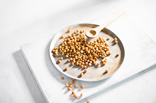 Image of crispy roasted chickpeas on an oven tray with wooden spoon