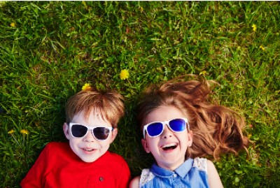 Two children lying on grass wearing sunglasses