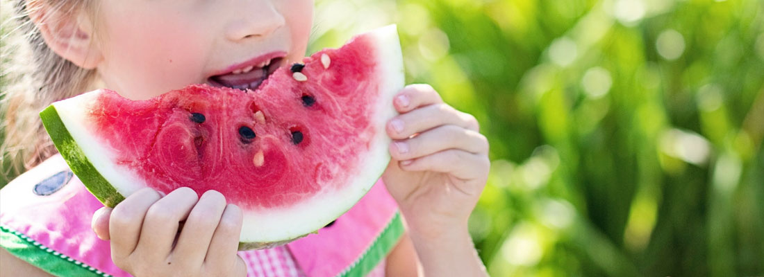young girl eating a slice of watermelon
